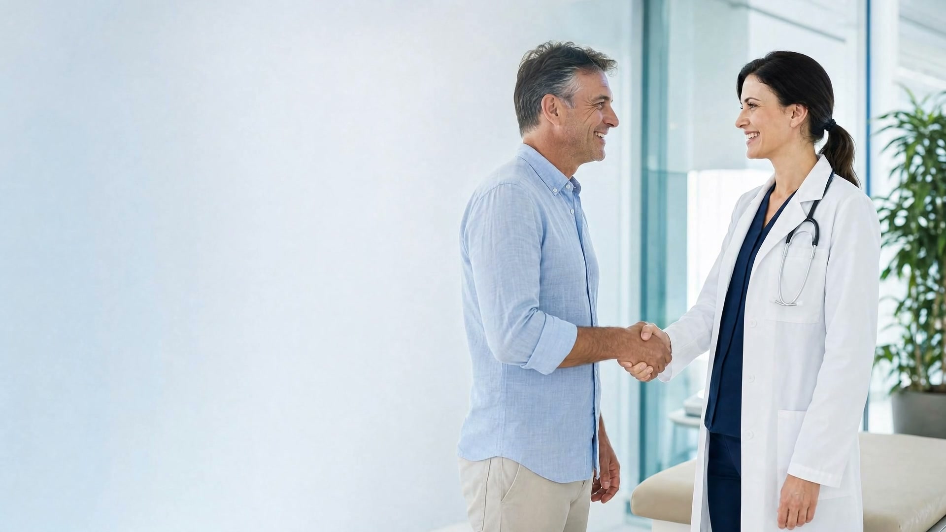A smiling patient shaking hands with a physician in a white lab coat